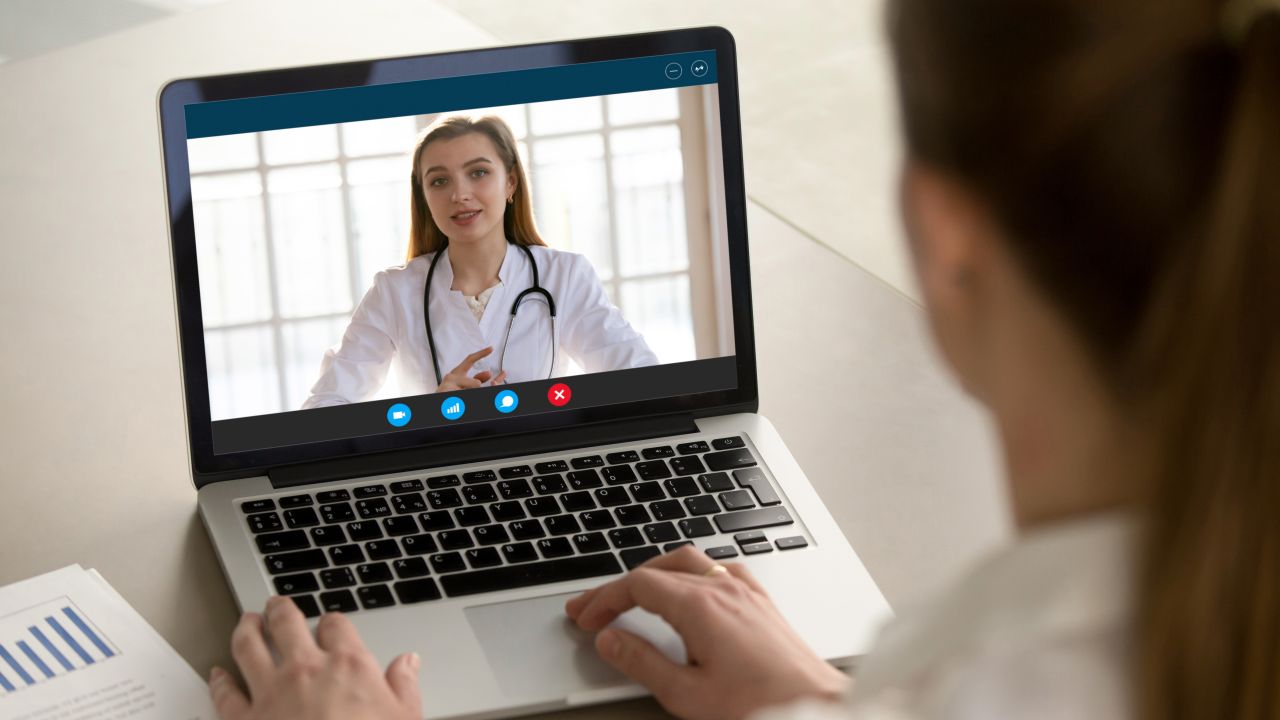 shoulder view young woman consulting with doctor online via video